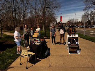 Students gather at an informational table focusing on the solar eclipse soundscapes project