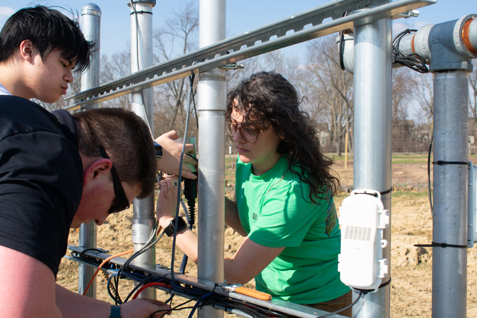 The Science Team connects the Solinst WLTS with the X-series logger and monitoring station near the pond at the Field Station.