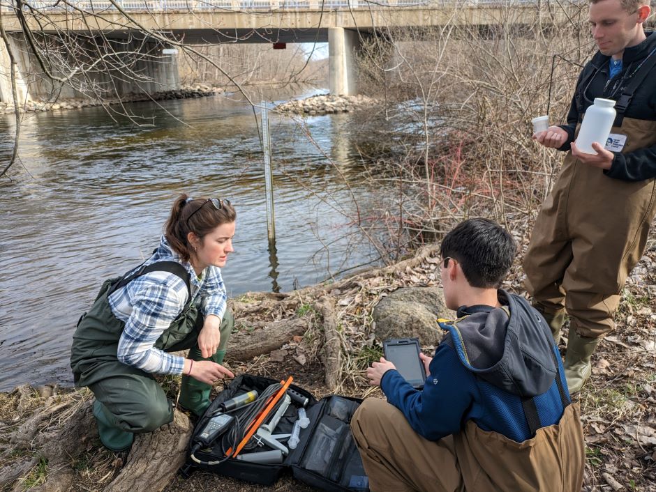 Kelly McCabe, coordinator of the HRWC Volunteer Chemistry and Flow Monitoring Program, trains intern, Alex Gonzalez, and a citizen science volunteer on sampling procedures along the banks of the Huron River north of Dexter, Michigan.