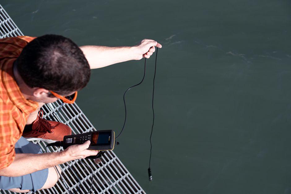 Janiak measuring dissolved oxygen off the side of the dock outside of the MarineGEO station. 